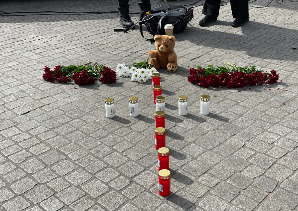 Ein Kreuz aus roten und weißen Blumen und Kerzen zum Gedenken an die gefallenen Ukrainerinnen und Ukrainer